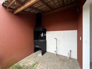Área externa com lareira preta e piso de tijolos.
