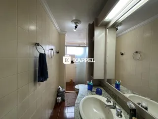 Banheiro com revestimento de azulejos brancos e bancada de mármore.