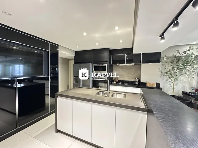 Cozinha moderna com armários pretos e bancadas claras.