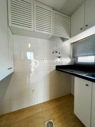 Foto de uma cozinha com armários brancos e piso de madeira clara.