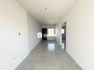 Corredor interno de uma residência com paredes brancas e piso de cerâmica.