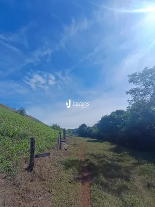 Paisagem rural com campo e cerca de madeira ao lado de um caminho.