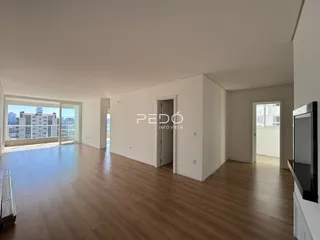 Sala de estar com piso de madeira e portas de vidro que dão vista para a cidade.