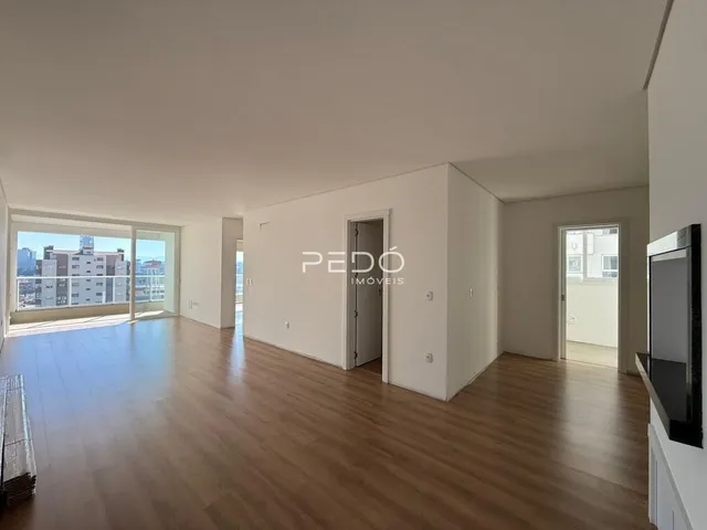 Sala de estar com piso de madeira e portas de vidro que dão vista para a cidade.
