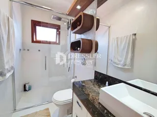 Foto de um banheiro com box de vidro e louças sanitárias.