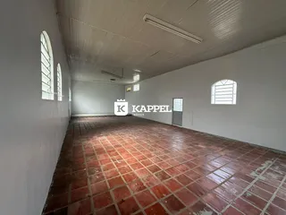 Foto de um corredor longo com piso de ladrilhos vermelhos e paredes brancas.