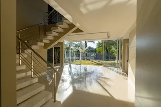 Espaço interno com acesso a uma área externa através de grandes portas de vidro.