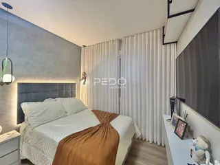 Quarto com cama e cortinas brancas em um apartamento.