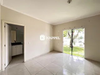 Sala de estar com piso de cerâmica e porta de vidro que dá acesso ao jardim.