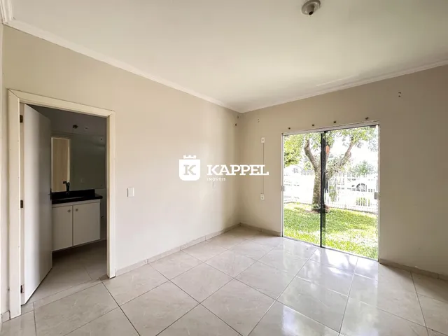 Sala de estar com piso de cerâmica e porta de vidro que dá acesso ao jardim.