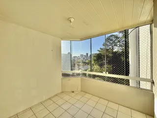 Vista interna de um ambiente com piso de cerâmica e uma sacada com vista para a vegetação.
