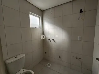 Um banheiro com paredes de azulejo claro e janela.