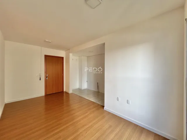 Hall de entrada com piso de madeira e porta de madeira na residência.