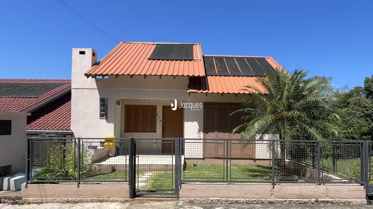 Fachada de uma casa residencial com telhado de telhas vermelhas e cerca frontal.
