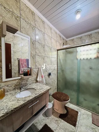 Foto interna de um banheiro com revestimento de azulejos e box de vidro.