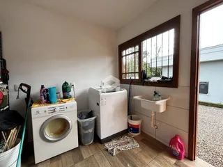 Interior de um cômodo com máquina de lavar e janela em Lajeado.