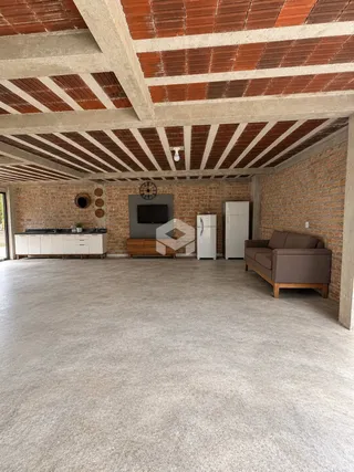Espaço interno com paredes de tijolo aparente e teto de concreto aparente.