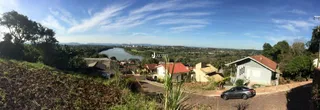 Paisagem de campo com água e vegetação sob um céu azul.