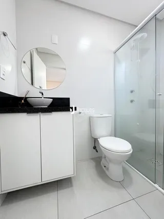 Banheiro moderno com box de vidro e vaso sanitário.