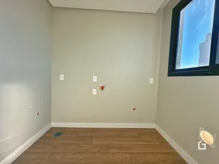 Parede interna de uma sala com piso de madeira e janela.