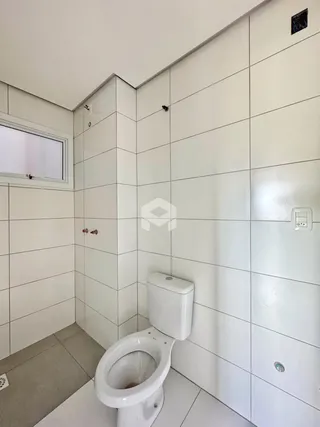Foto do interior de um banheiro com revestimento cerâmico branco.