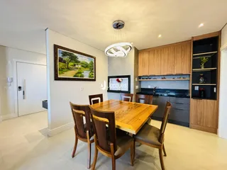 Uma sala de jantar com mesa de madeira e cadeiras em um imóvel no Brasil.