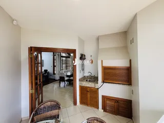 Interior de uma passagem com porta de madeira e piso de cerâmica.