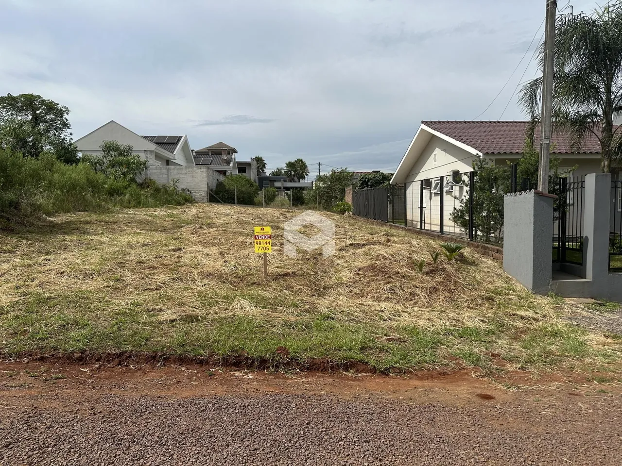 Vista da propriedade com terreno gramado em primeiro plano e casas ao fundo.