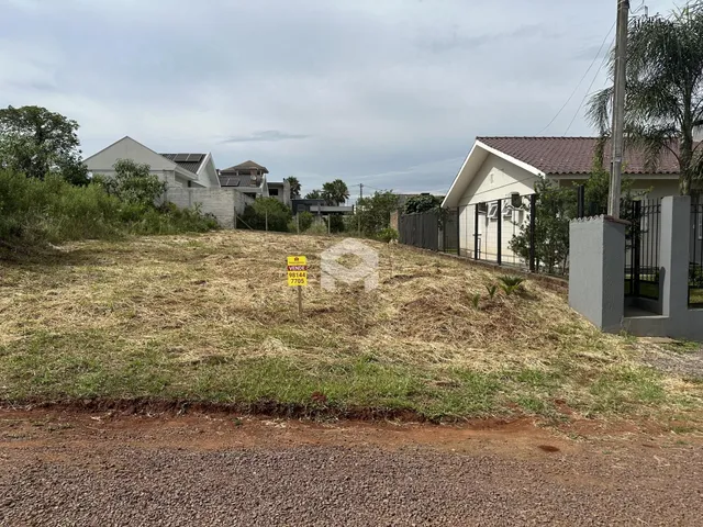 Vista da propriedade com terreno gramado em primeiro plano e casas ao fundo.