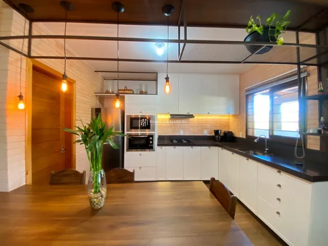 Cozinha com armários brancos e piso de madeira clara.