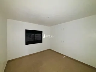 Interior de uma sala de estar com paredes brancas e piso bege.