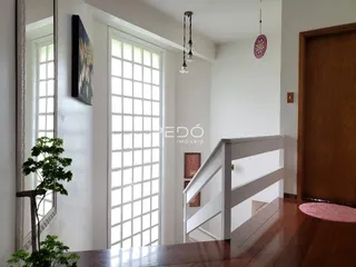 Interior de uma sala com piso de madeira e escadaria em uma residência.