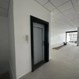 Hall de entrada com paredes brancas e porta visível.