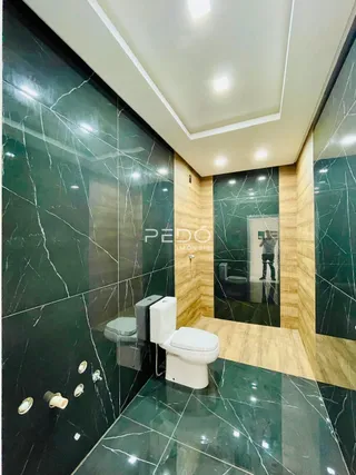Interior de um banheiro com revestimento em mármore verde escuro.