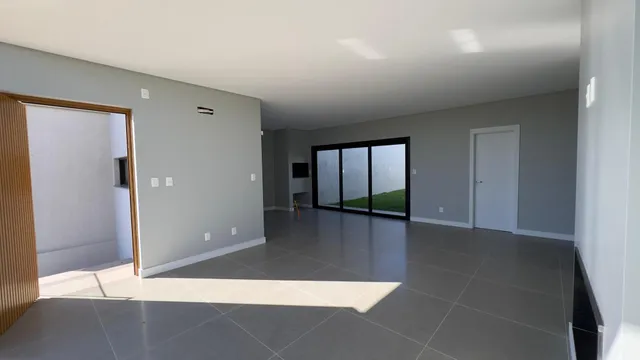 Ambiente interno moderno com piso de porcelanato e grandes janelas que dão vista para o exterior.