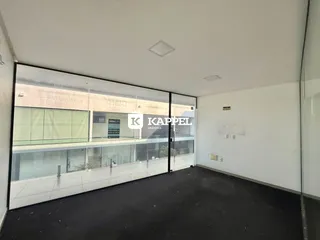 Ambiente interno com grandes janelas que oferecem uma vista para a rua.