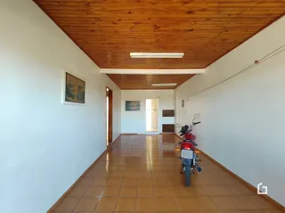Corredor interno com piso de cerâmica e teto de madeira.