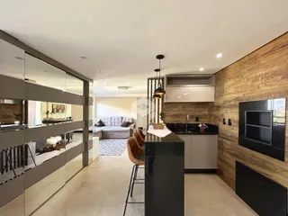 Interior de uma sala de estar com cozinha e divisória de vidro em um imóvel.