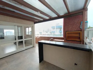 Vista de uma área externa coberta com parede de tijolos vermelhos e portas de vidro.