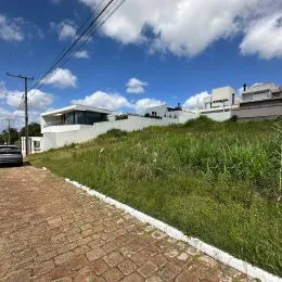 Vista externa de uma propriedade em Lajeado, mostrando um muro branco e área gramada.