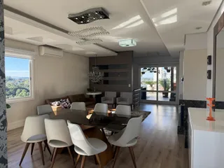 Sala de jantar com mesa de madeira e vista para a paisagem externa.