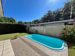 Vista externa de uma piscina com deck e jardim em Lajeado.