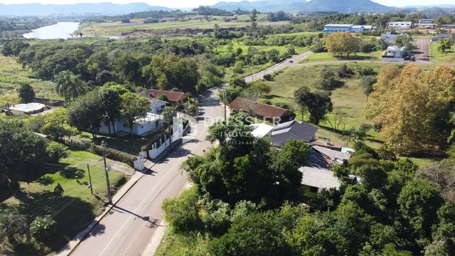 Vista aérea de uma propriedade rural com vegetação densa e estrada.
