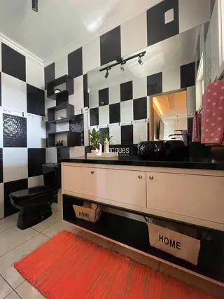 Ambiente de banheiro com revestimento de azulejos preto e branco e bancada branca.