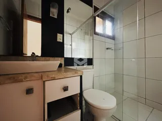 Foto de um banheiro com box de vidro e vaso sanitário.