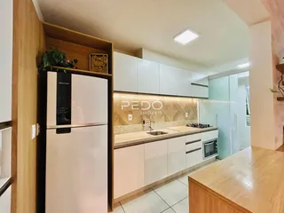 Vista da cozinha moderna com armários brancos e bancadas claras.
