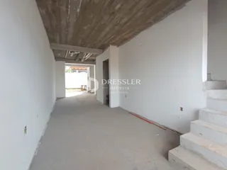 Corredor interno de um imóvel com teto de concreto aparente e paredes brancas.