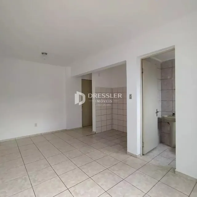 Interior de uma sala com piso de cerâmica clara e paredes brancas.