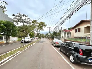 Vista da rua em Lajeado, Brasil, mostrando casas e veículos.