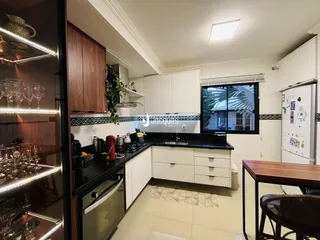 Interior da cozinha com armários de madeira e bancadas escuras.